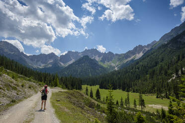 Wanderer mit Blick auf das Karwendelgebirge, während er auf einem Wanderweg in Tirol, Österreich, steht - LBF03334