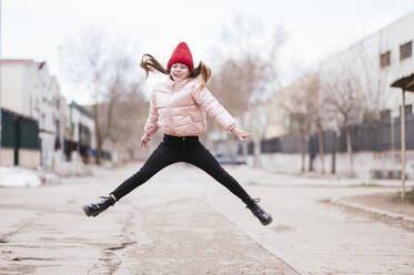 Lachendes Mädchen springt auf der Straße gegen den Himmel - JCMF01888