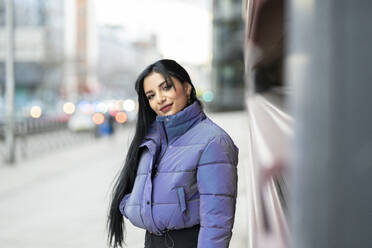 Beautiful young woman in warm clothing standing on street during winter - JCCMF01191