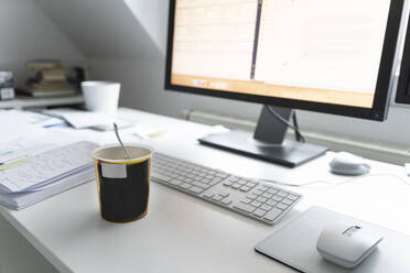 Computer mit Tasse und Tagebuch auf dem Schreibtisch im Heimbüro - CHPF00743