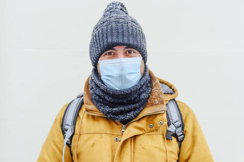 Man in warm clothing against white wall during pandemic stock photo