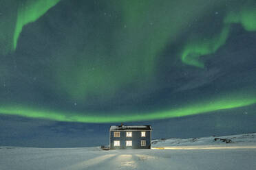 Nordlicht (Aurora borealis) auf dem beleuchteten Haus im Schnee, Veines, Kongsfjord, Varanger Halbinsel, Finnmark, Norwegen, Skandinavien, Europa - RHPLF19151