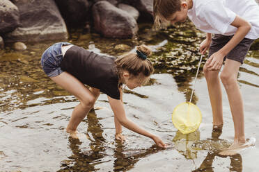 Brother and sister fishing in sea during vacation - MASF21763