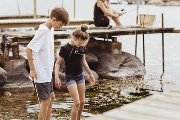 Siblings fishing in sea during summer vacation - MASF21767