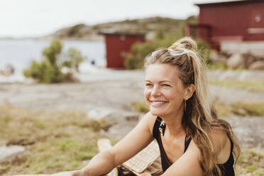 Lächelnde Frau schaut beim Picknick am Hafen weg - MASF21787