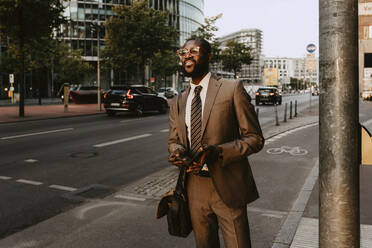 Männlicher Unternehmer schaut weg, während er auf einem Fußweg in der Stadt steht - MASF21814