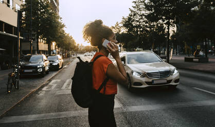 Female entrepreneur talking on smart phone while crossing street in city - MASF21817