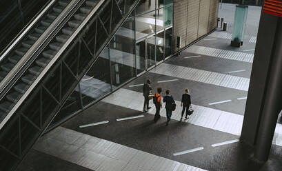 Rückansicht eines weiblichen und eines männlichen Mitarbeiters, die sich auf einem Fußweg unterhalten - MASF21828