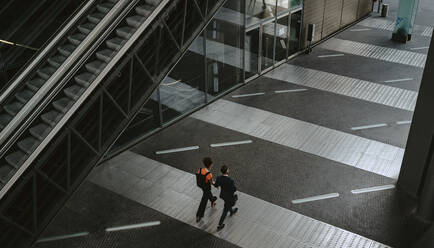 Rear view of businessman discussing with female colleague on walkway - MASF21837