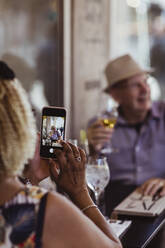 Ausgeschnittenes Bild einer Frau, die einen Mann fotografiert, während sie in einem Café sitzt - MASF21856