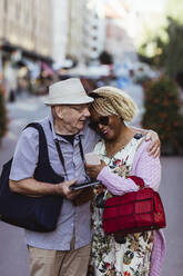 Senior man embracing woman while standing on street in city - MASF21876