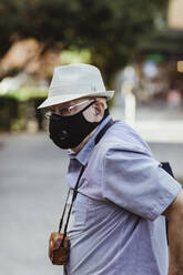 Senior man with protective face mask standing in park - MASF21886