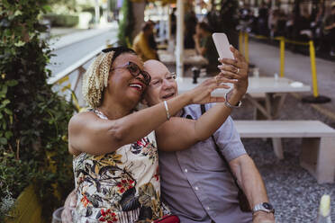 Fröhliches heterosexuelles Paar, das ein Selfie mit seinem Smartphone in einem Café macht - MASF21895