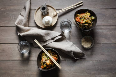 Napkin, two glasses of water and two bowls of vegan pasta with vegetables and sesame seeds - EVGF03899