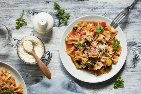 Two plates of bow tie pasta with vegetables and vegan Parmesan - EVGF03902