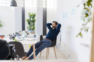 Entspannter männlicher Unternehmer mit geschlossenen Augen im Büro sitzend - GIOF11076