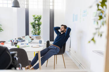 Relaxed male entrepreneur with eyes closed sitting in office - GIOF11076