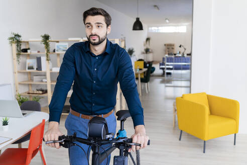 Männlicher Unternehmer mit Fahrrad im Büro - GIOF11093
