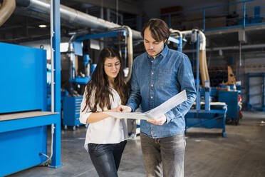 Ein Inspektor arbeitet mit einem Kollegen über einem Dokument, während er in der Industrie steht - DIGF14361