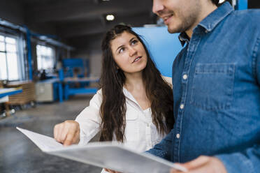 Colleagues having discussion over document while standing in industry - DIGF14362