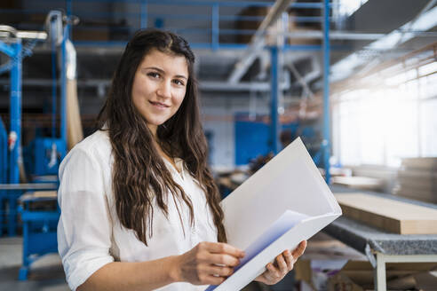 Lächelndes Fachwissen beim Überprüfen von Papierkram in der Industrie - DIGF14370