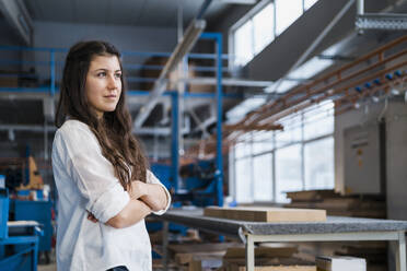 Confident female expertise with arms crossed looking away while standing at industry - DIGF14371