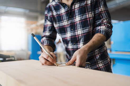 Handwerker, der bei der Arbeit in der Industrie Holz misst - DIGF14378