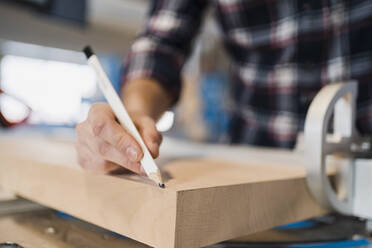 Industrial worker drawing on wood with pencil while standing at industry - DIGF14379