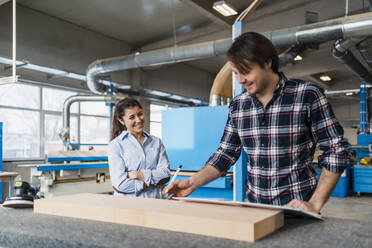 Handwerker, der Holz misst, während er bei einem Kollegen in der Industrie steht - DIGF14381