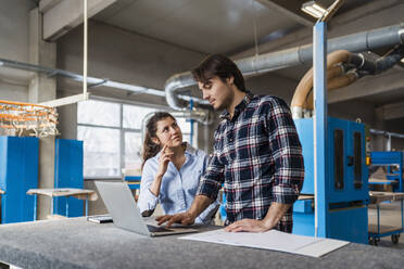 Young expertise team working over laptop while standing at industry - DIGF14392