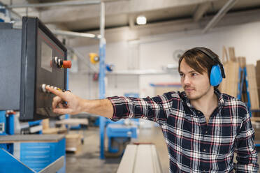 Industrial worker operating machine while standing at industry - DIGF14404