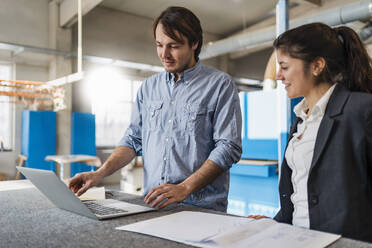 Business people working over laptop while standing in industry - DIGF14408