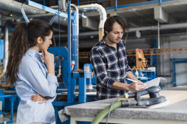 Sachkenntnis beim Erklären eines Dokuments für einen Kollegen im Stehen in der Industrie - DIGF14469