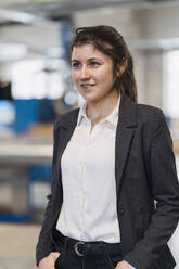 Female entrepreneur looking away while standing at industry - DIGF14495