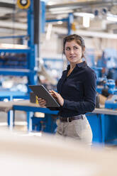Junge Geschäftsfrau, die ein digitales Tablet benutzt, während sie in der Industrie steht - DIGF14513