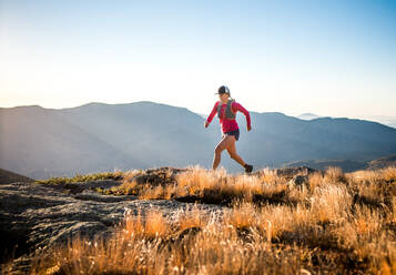 Woman running in the White Mountains at sunrise in summer - CAVF92327