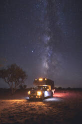 A small pickup RV is on a camping spot under the Milky Way - CAVF92351