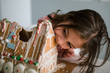 Junges weibliches Kind isst Lebkuchenhaus großen Bissen - CAVF92402