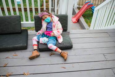 Little girl in crown slumped on deck tired from birthday party - CAVF92404