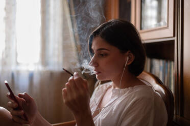 Female smoker browsing mobile phone - CAVF92411