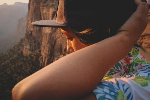 Boy in Hawaiian Shirt Looks Down the Desert Canyon at Sunset. - CAVF92537