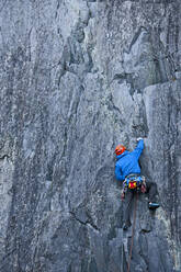 Man climbing up steep rock face at Slate quarry in North Wales - CAVF92570