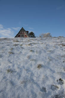 Das Dach des Hauses lugt hinter dem schneebedeckten Deich hervor - GISF00760