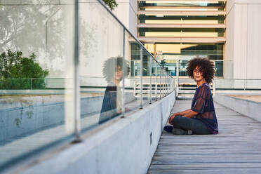 Woman sitting at the exit of a building in the city. - CAVF92610