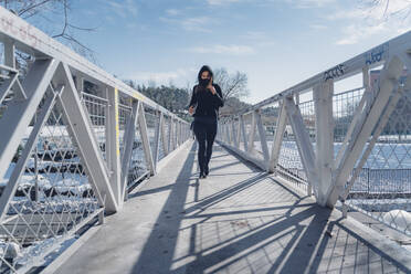 Attractive young brunette woman running through the city after a big snow storm - CAVF92618