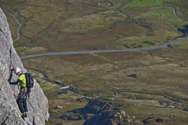 Mann klettert an der Felswand des Tryfan in Nordwales - CAVF92643