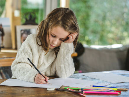 Crop kleines Mädchen Zeichnung mit bunten Bleistiften auf Papier Blatt in hellen Raum - ADSF20676