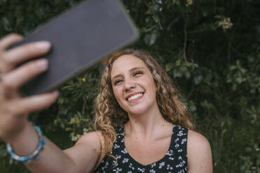 Schöne lächelnde Frau nimmt Selfie im öffentlichen Park - DSIF00313