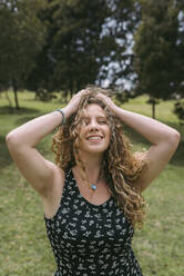 Sinnliche schöne Frau mit Hand in den Haaren steht im Park während des sonnigen Tages - DSIF00319
