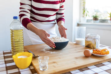 Woman with flour bowl on cutting board in kitchen at home - WPEF03985